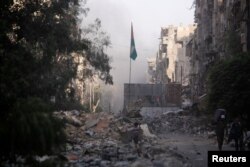 A boy stands on the rubble of damage buildings in Yarmouk Palestinian camp in Damascus, Syria, May 21, 2018.