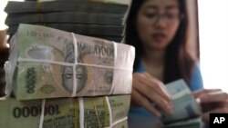 A woman counts Vietnamese dong bank notes in the office of a local company in Hanoi (File)