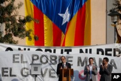 FILE - Catalan regional President Quim Torra, center, applauds in front of a large Catalonia independence flag during a rally in Sant Julia de Ramis, Spain, Oct. 1, 2018.