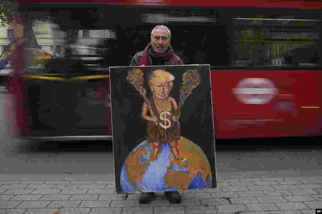 Political artist Kaya Mar poses with a painting of U.S. president-elect Donald Trump, outside Downing Street in London, Nov. 6, 2024.