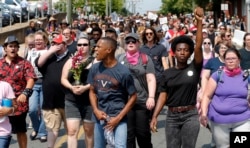 Demonstrators against racism march along city streets as they mark the anniversary of last year's Unite the Right rally in Charlottesville, Va., Sunday, Aug. 12, 2018.