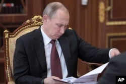 Russian President Vladimir Putin reads papers during a meeting in the Kremlin, in Moscow, Russia, Jan. 16, 2017.