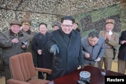 FILE - North Korean leader Kim Jong Un (C) smiles as he guides a test fire of a new multiple launch rocket system in this undated photo released by North Korea's Korean Central News Agency in Pyongyang, March 4, 2016.