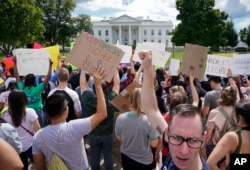 Malcolm McCluskey, right, pumps his fist in the air as he joins in a chant with supporters of Deferred Action for Childhood Arrival program (DACA) during a demonstration on Pennsylvania Avenue in front of the White House in Washington, Sept. 9, 2017.