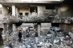 Guards stand on the rubble of a house hit by Saudi-led air strikes in Sanaa, Yemen, January 18, 2022.