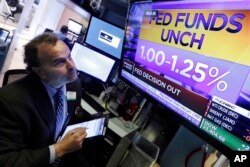 Trader Gerard Farco watches a television on the floor of the New York Stock Exchange showing the rate decision of the Federal Reserve, Nov. 1, 2017. With a new Federal Reserve leader announced, the Fed is keeping its key interest rate unchanged.