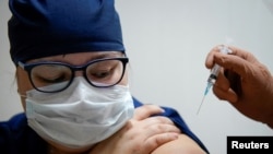 FILE - A medic at a regional hospital receives Russia's 'Sputnik-V' vaccine shot against the COVID-19 disease in Tver, Russia, Oct. 12, 2020. 