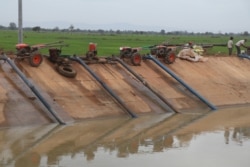 Farmers use two-wheel tractors to pump water from a twenty-kilometer irrigation system built by a Chinese company in Cambodia's western Pursat province, December 18, 2019. (Sun Narin/VOA Khmer)