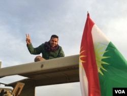 An Iraqi Kurdish Peshmerga soldier flashes a victory sign as he sits atop his vehicle on the Makhmour frontline, where Iraqi forces took their first step in the battle for Mosul by trying to capture villages southeast of the IS-held city, March 24, 2016. (S.Behn / VOA)