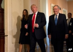 FILE - President-elect Donald Trump, accompanied by his wife, Melania, and Senate Majority Leader Mitch McConnell of Ky., gestures while walking on Capitol Hill in Washington, Nov. 10, 2016.