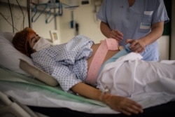 Seorang perawat tengah membantu ibu hamil yang terpapar COVID-19 di Paris, Prancis, 17 November 2020. (Martin BUREAU / AFP)