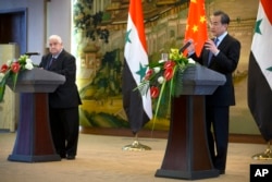 China's Foreign Minister Wang Yi, right, speaks at a press briefing with Syria's Foreign Minister Walid al-Moallem at China's Ministry of Foreign Affairs in Beijing, Dec. 24, 2015.