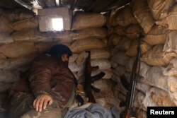 A rebel fighter rests with his weapons behind sandbags at insurgent-held al-Rashideen, Aleppo province, Syria, Dec. 30, 2016.