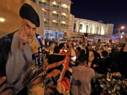 Pendukung ulama Syiah Irak Muqtada al-Sadr mengendarai kendaraan saat merayakan di pusat kota suci Najaf setelah penutupan tempat pemungutan suara saat pemilihan parlemen awal pada 10 Oktober 2021. (Foto: AFP)