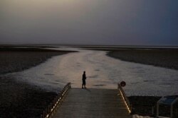 A person walks on a boardwalk at the salt flats at Badwater Basin, Aug. 17, 2020, in Death Valley National Park, California.