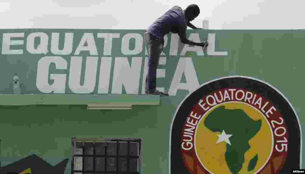 Un traveilleur passe un coup de peinturw sur le haut du mur avant l'ouverture de la Coupe d'Afrique des Nations samedi au stade de Bata, en Guinée équatoriale, le vendredi 16 janvier 2015.