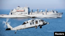 FILE - An MH-60S Sea Hawk helicopter prepares to land on the flight deck of aircraft carrier USS Harry S. Truman during a vertical replenishment in the Arabian Gulf. The announcement of joint patrols with the Philippines comes as China continues to act aggressively over disputed territories in the South China Sea.