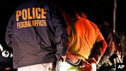 FILE - In this Oct. 22, 2018, photo U.S. Immigration and Customs Enforcement agents surround and detain a person during a raid in Richmond, Va. 