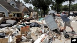 Sukarelawan Paul Hancock membuang sebuah oven yang rusak akibat banjir ke tumpukan puing-puing setelah Badai Harvey melanda, 3 September 2017, di Spring, Texas. 