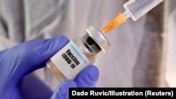 Seorang wanita memegang botol kecil berlabel vaksin Covid-19 sebagai ilustrasi. (Foto: Reuters/Dado Ruvic)