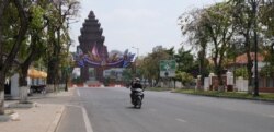 អ្នកដំណើរបើកបរម៉ូតូលើដងវិថីមួយ ក្នុងរាជធានីភ្នំពេញ ក្នុងអំឡុងពេលមានការឆ្លងជំងឺកូវីដ១៩ ក្នុងសហគមន៍លើកទីបី នៅរាជធានីភ្នំពេញប្រទេសកម្ពុជា កាលពីថ្ងៃទី២៤ ខែកុម្ភៈ ឆ្នាំ២០២១។ (ទុំ ម្លិះ/វីអូអេ)