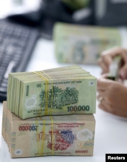 បុគ្គលិក​ធនាគារ​ម្នាក់​រាប់​លុយ​ដុង​របស់​វៀតណាម​នៅ​ក្នុង​ក្រុង Vinh Yen ប្រទេស​វៀតណាម។