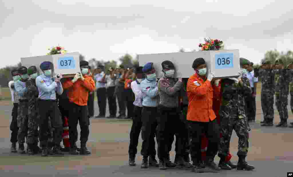 Para anggota Basarnas dan tentara Indonesia mengangkat peti mati jenazah korban jatuhnya pesawat AirAsia bernomor penerbangan 8501 di bandar udara di Pangkalan Bun (5/1). (AP/Tatan Syuflana)