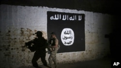 FILE - An Iraqi soldier inspects a tunnel, adorned with an Islamic State group flag, March 1, 2017.