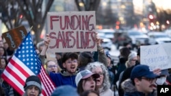 FILE - People protest a funding freeze of federal grants and loans following a push from President Donald Trump to pause federal funding, near the White House in Washington, Jan. 28, 2025.