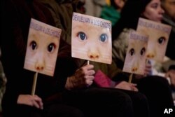Warga menggenggam plakat bergambar bayi bertuliskan "Kembali(kan) ke Anak-anak" dalam bahasa Spanyol, di luar pengadilan Buenos Aires, Argentina (5/7).