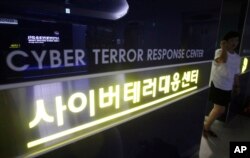 FILE - A woman walks by a sign at Cyber Terror Response Center of National Police Agency in Seoul, South Korea.
