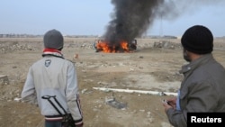 Sunni Muslim fighters watch as a police vehicle burns during clashes in Ramadi, Jan. 2, 2014.