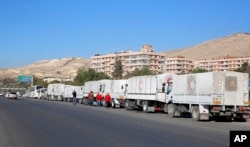 A convoy of humanitarian aid waits in front of the United Nations Relief and Works Agency (UNRWA) offices before making their way into the government besieged rebel-held towns of Madaya, Zabadani and Moadimayet al-Sham in the Damascus countryside, as part of a U.N.-sponsored aid operation, in Damascus, Syria, Feb. 17, 2016.