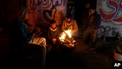 Des Palestiniens, qui ne reçoivent que quelques heures d'électricité par jour, se réchauffant autour d'un feu devant chez eux à Gaza.