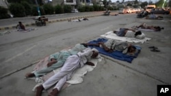 Para buruh tidur di pinggir jalan pada pagi hari musim panas yang terik di Karachi, Pakistan (29/5). Gelombang udara panas sedang melanda India dan Pakistan. 