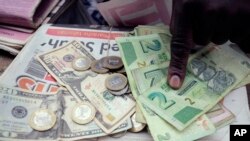 FILE - A man counts Zimbabwean dollar notes and coins next to a ten US dollar note on the streets of Harare, June 25, 2019. 