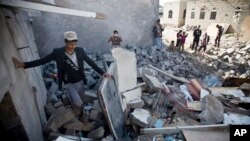 Orang-orang berkumpul dekat reruntuhan rumah-rumah yang hancur akibat serangan udara Arab Saudi dekat bandara di Sana'a, Yaman, 31 Maret 2015. 