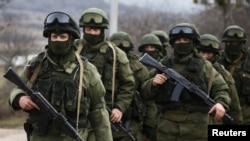 FILE - Armed men, Russian servicemen as the Kremlin later admitted, stand guard outside a Ukrainian military base in Perevalne, Crimea, March 9, 2014. Moscow's initial denials that the men were its soldiers was seen as part of its disinformation strategy.