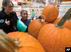 Para siswa dan guru dari Mundo Verde Bilingual Public Charter School di Washington memperhatikan labu-labu dan produk lainnya dalam kunjungan ke Pasar timur di ibu kota, 13 Oktober 2017.
