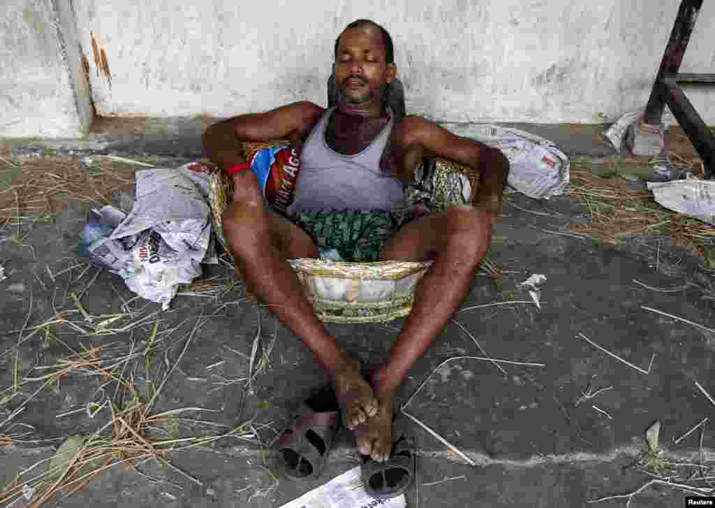 A laborer takes a nap in a basket at a wholesale vegetable market during a heat wave in Kolkata, May 25, 2015.&nbsp;