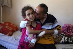 Suzy Ishkontana, 7 tahun, dicium ayahnya Riad Ishkontana, di Shifa Hospital, Gaza City (18/5). Ibu dan ke-4 saudara kandung Suzy meninggal dalam serangan udara Israel.