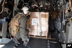In this image provided by the U.S. Navy, Marines attached to the 26th Marine Expeditionary Unit, embarked aboard the amphibious assault ship USS Kearsarge, load military field rations at Luis Munoz Marin Airport in San Juan, Sept. 25, 2017.