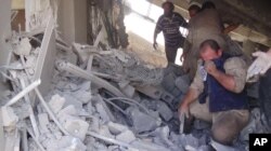 FILE - This image posted on the Twitter account of Syria Civil Defence, also known as the White Helmets, a volunteer search and rescue group, shows the aftermath of an airstrike in Talbiseh, Syria, Sept. 30, 2015.