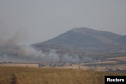 FILE - Smoke rises over Golan Heights as it's seen from Deraa area, Syria July 6, 2018.