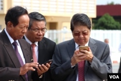 Senior Cambodian government officers are using their smart phones while awaiting the return of Cambodian Prime Minister Hun Sen from France at Phnom Penh International Airport, October 28, 2015.