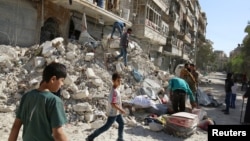 Warga mengangkut barang-barang dari lokasi permukiman yang terkena serangan udara di distrik al-Qaterji, Aleppo, Suriah (17/10). 