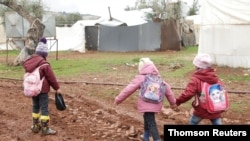 Internally displaced Syrian children walk in mud near tents at a camp in northern Aleppo near the Syrian-Turkish border.