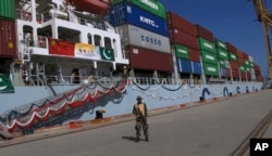 A Pakistan soldier stands guard while a loaded Chinese ship prepares to depart Gwadar port, about 700 kilometers (435 miles) west of Karachi. Nov. 13, 2016.