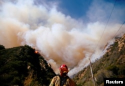 Firefighters battle the Woolsey Fire as it continues to burn in Malibu, California, Nov. 11, 2018.