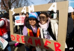 FILE - Demonstrators Karina Velasco, left, and Gabi Sanchez hold a sign during an immigration rally in support of the Deferred Action for Childhood Arrivals (DACA), and Temporary Protected Status (TPS), programs, on Capitol Hill in Washington, Dec. 6, 2017.